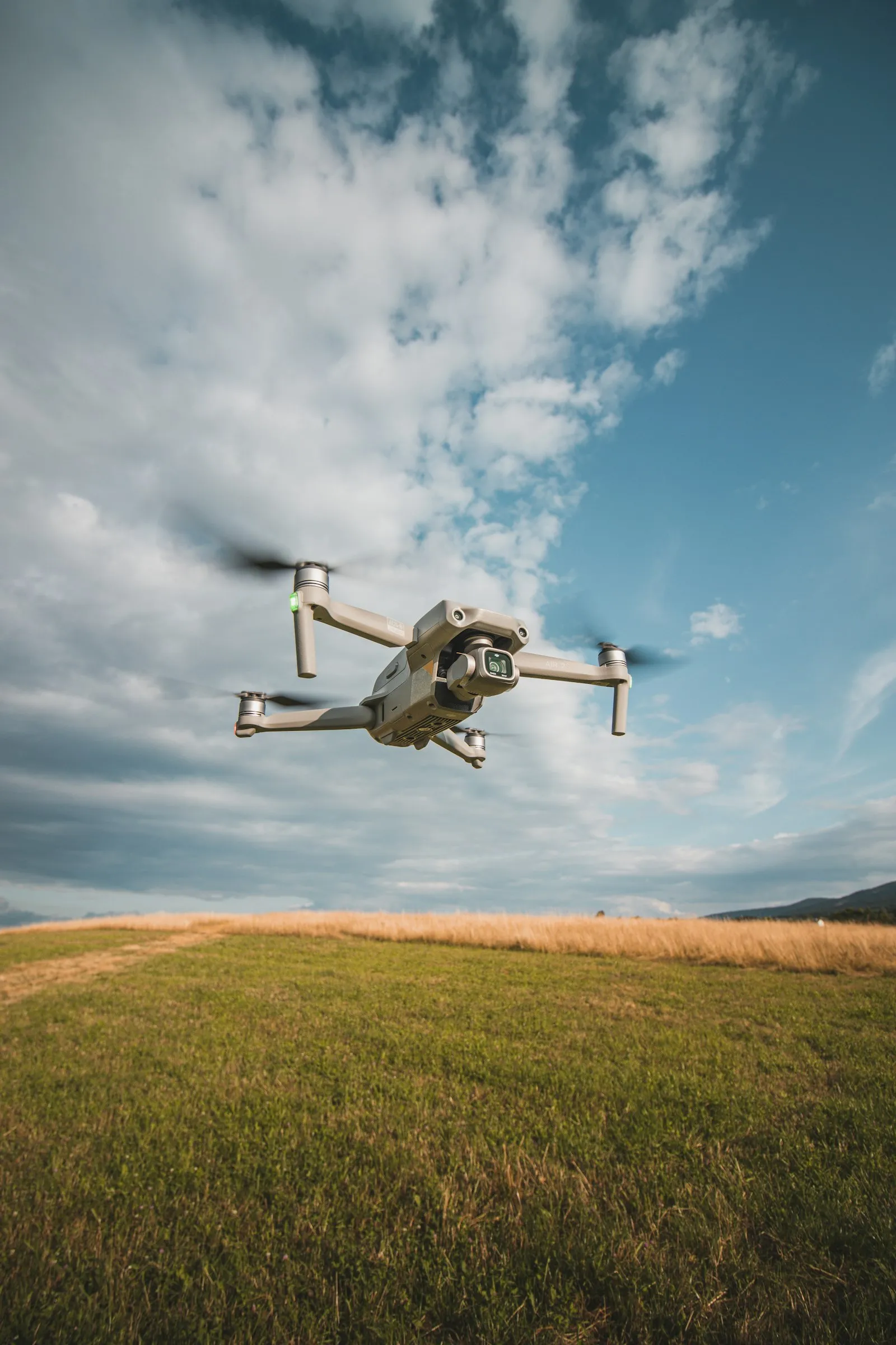Dron en vuelo sobre un campo bajo un cielo con nubes