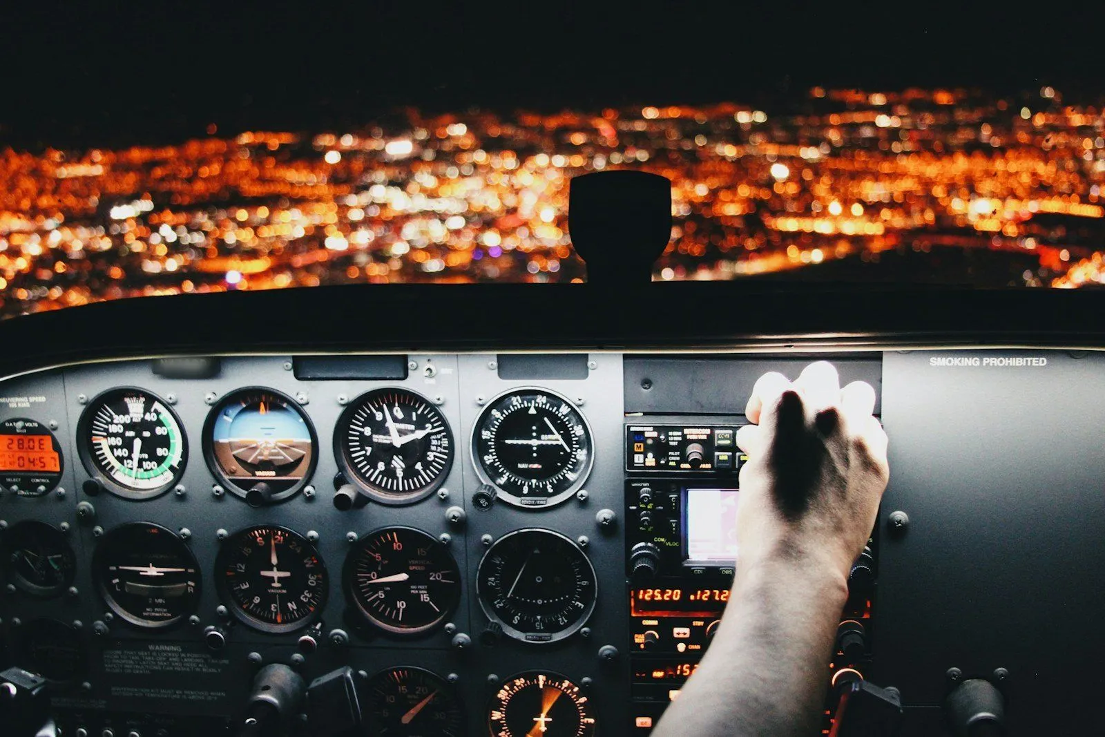 Mano de un piloto en la palanca de potencia, de noche sobre las luces de una ciudad